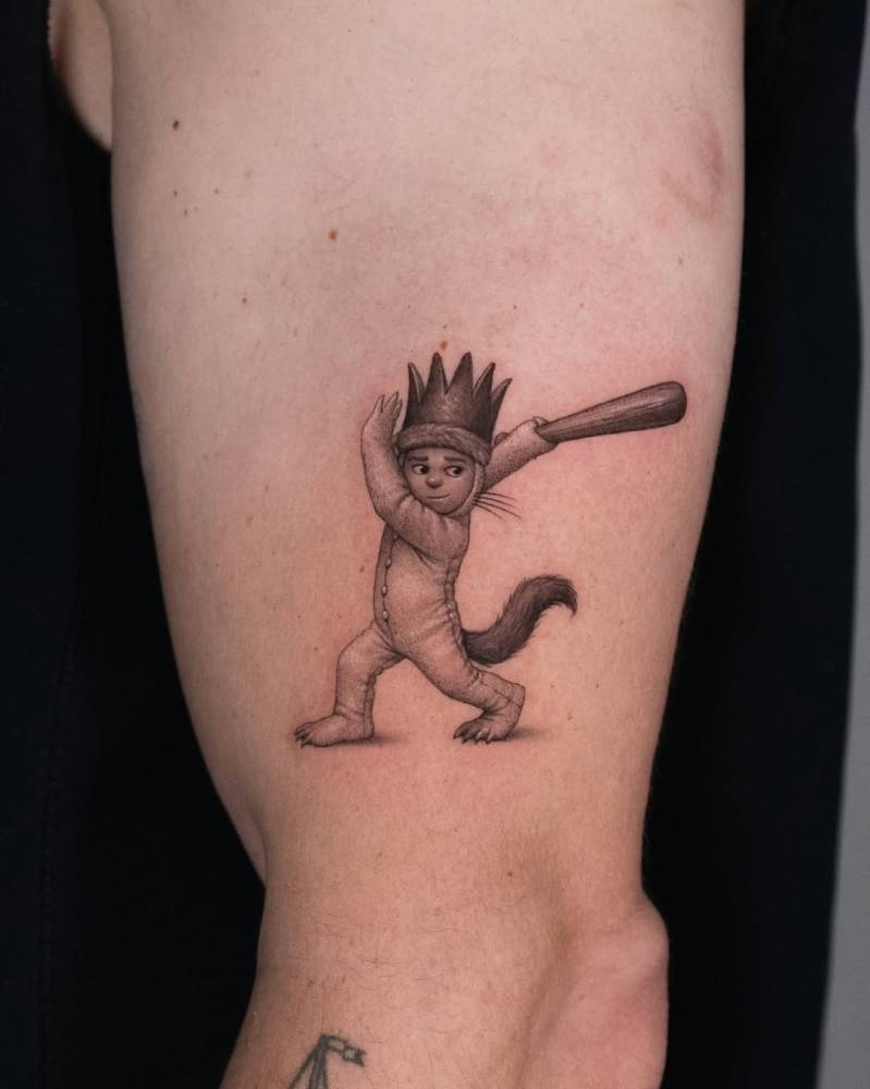 Cartoon style 'Where the Wild Things Are' tattoo located on the upper arm.