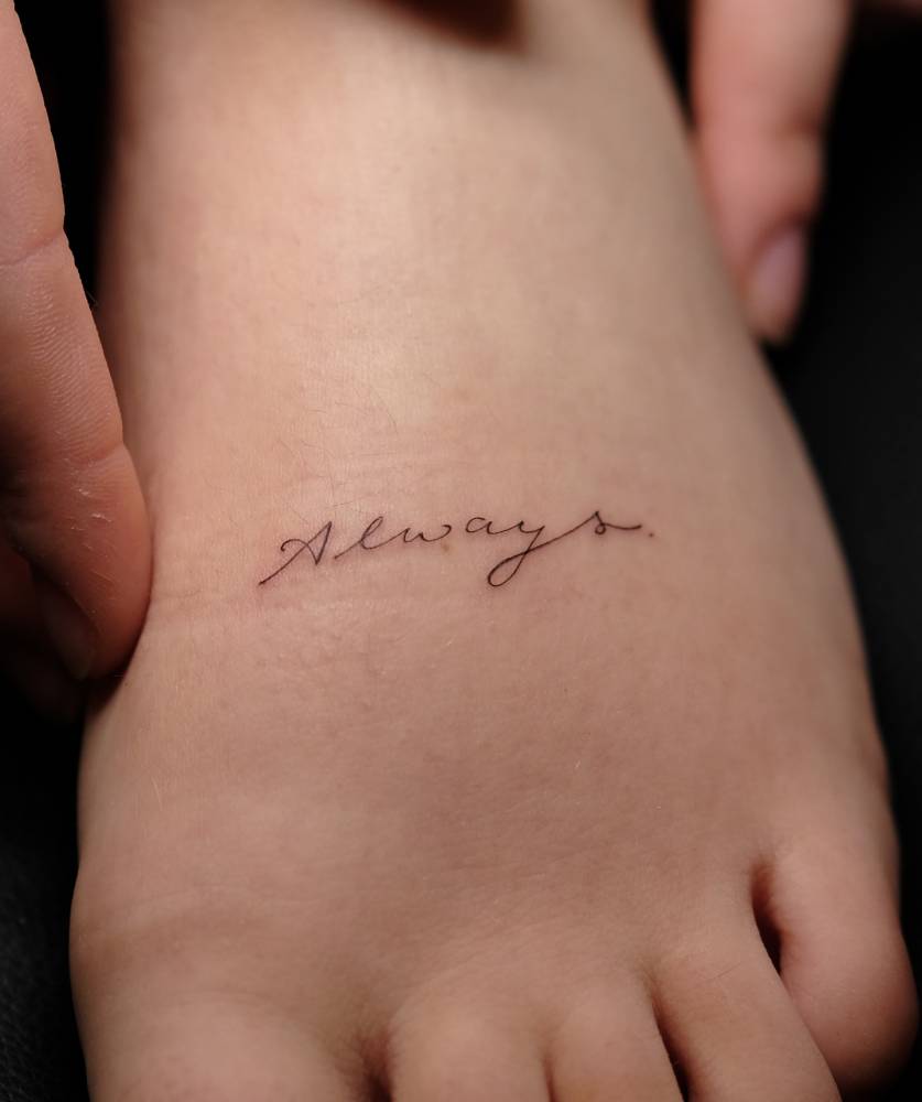 Handwritten font word "always" tattooed on the foot.