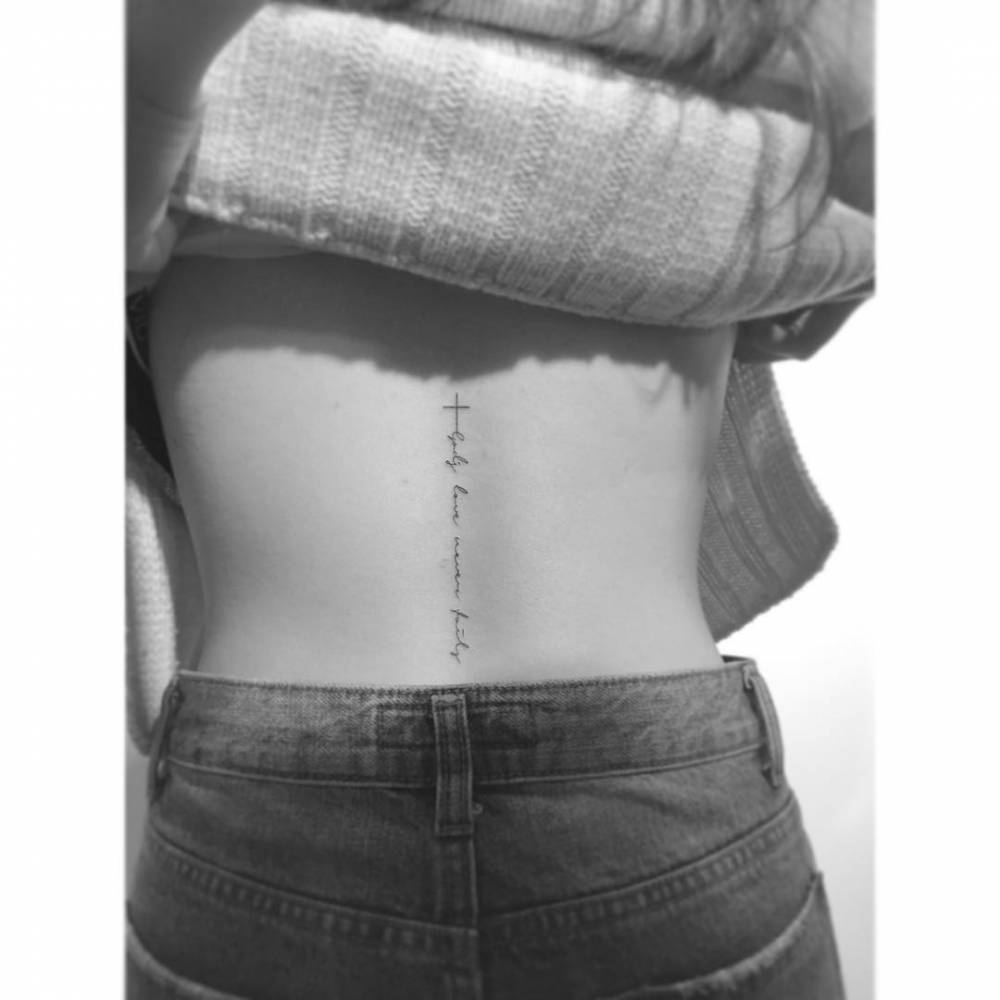 Cross and handwritten quote tattooed on the lower back.
