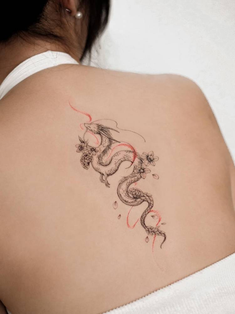 Illustrative style dragon tattoo located on the upper back.