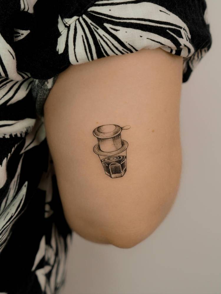 Vietnamese coffee filter tattooed on the tricep, done in illustrative style.