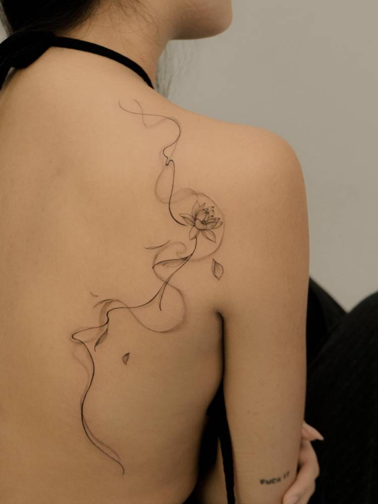 Lotus flower tattoo located on the back, illustrative style.
