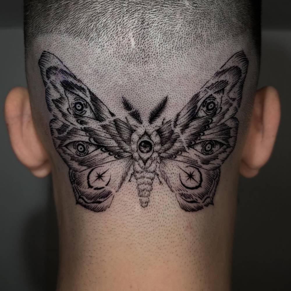 Blackwork style moth tattoo located on the head.