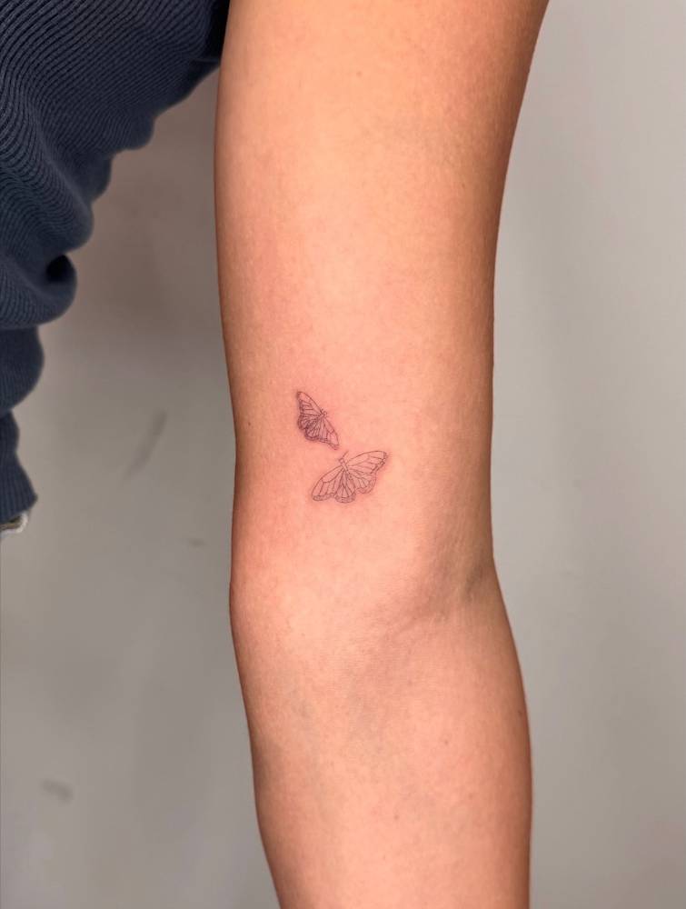 Single needle butterfly couple tattoo located on the inner arm.