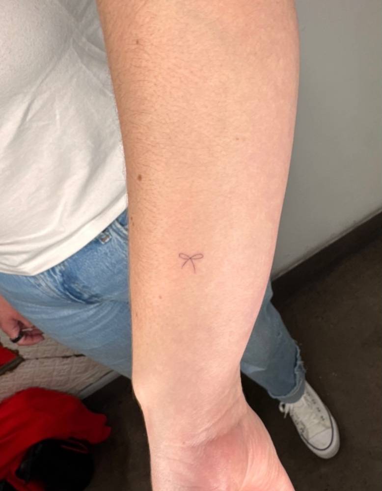 Tiny minimalistic bow tattooed on the wrist.