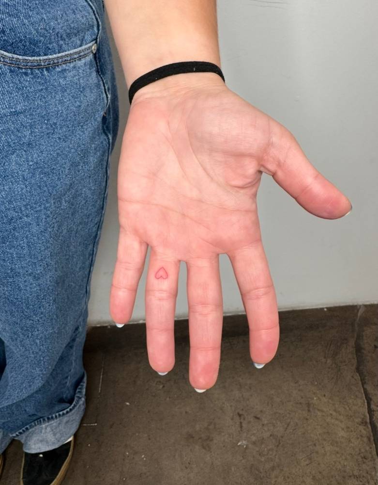 Minimalistic style red heart tattoo done on the finger.