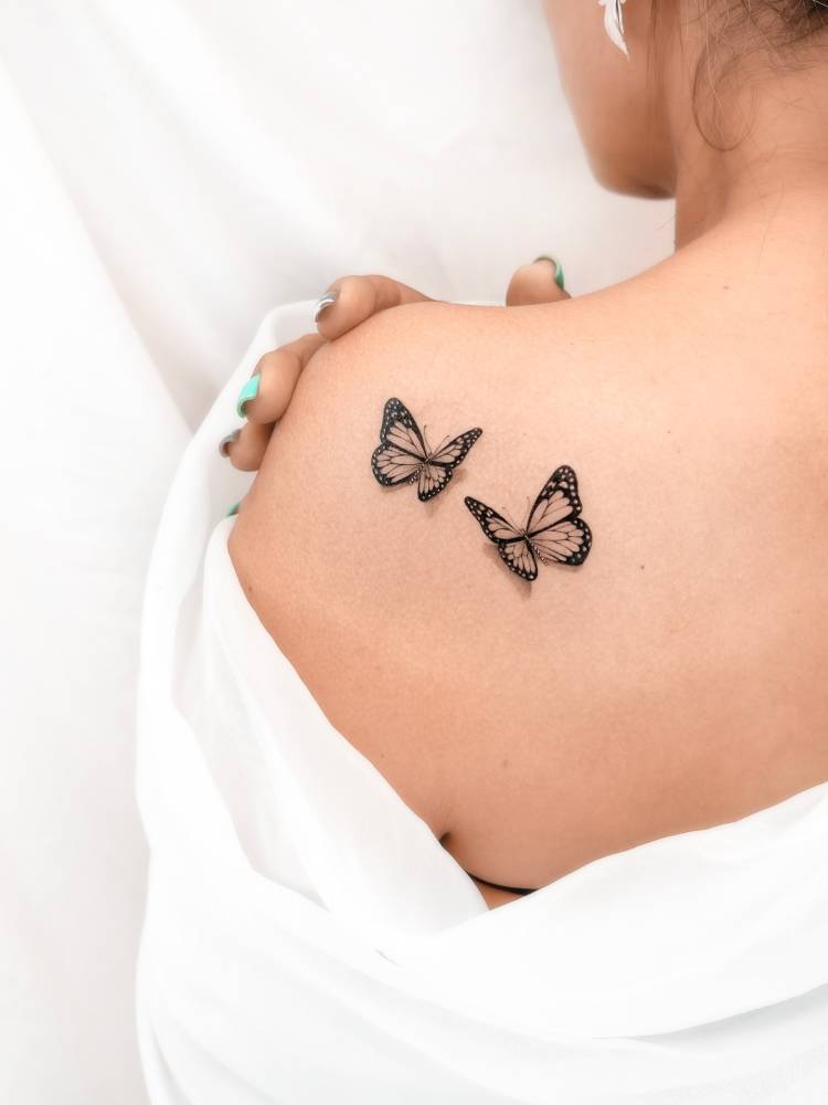 Micro-realistic style butterfly couple tattoo placed on the shoulder blade.