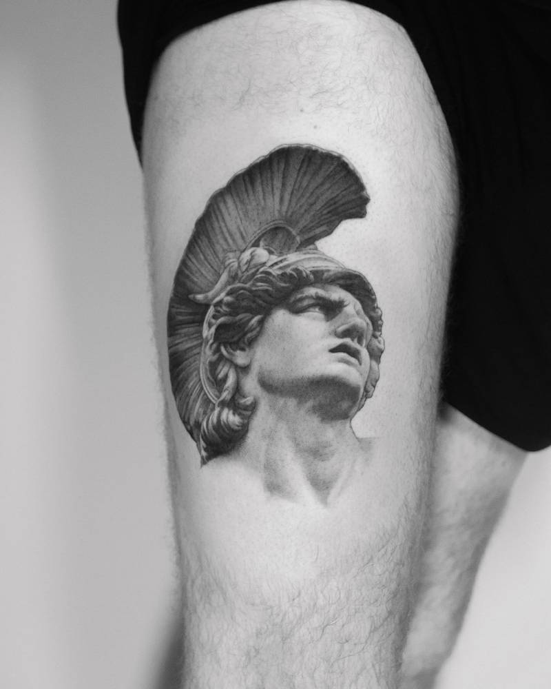 Achilles portrait tattoo in black and grey style located on the thigh.