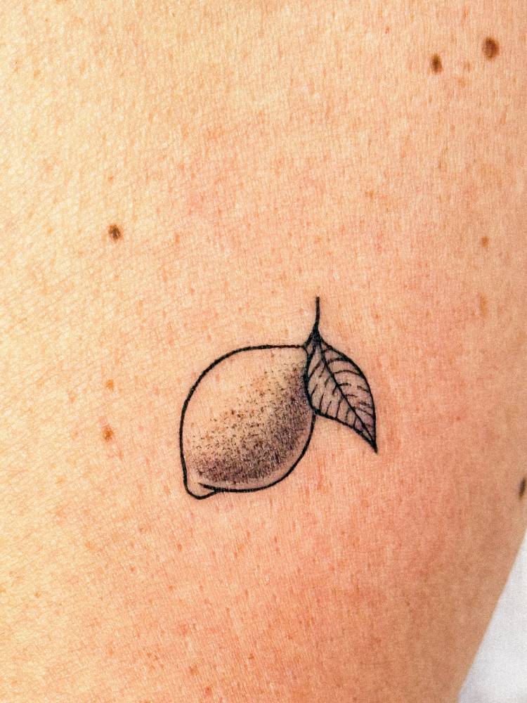 Illustrative style lemon tattoo located on the upper arm.