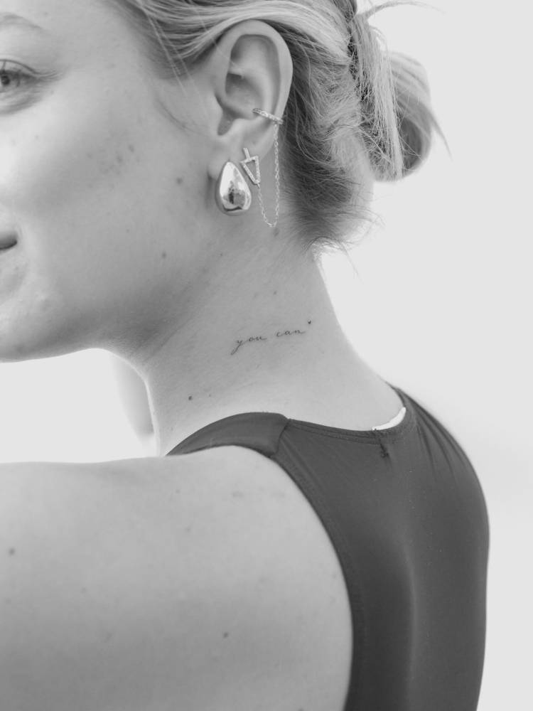 Script font "you can" lettering tattoo located on the neck.