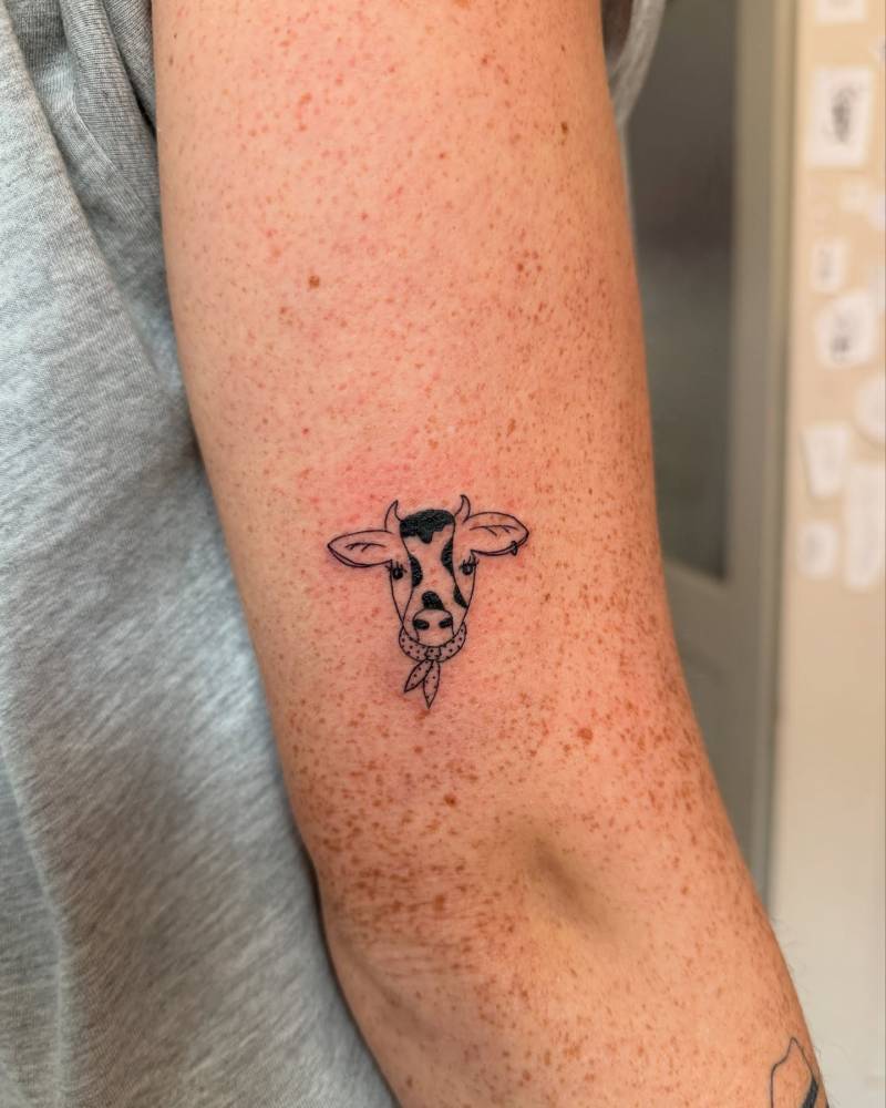 Cow portrait tattoo in illustrative style placed on the tricep.