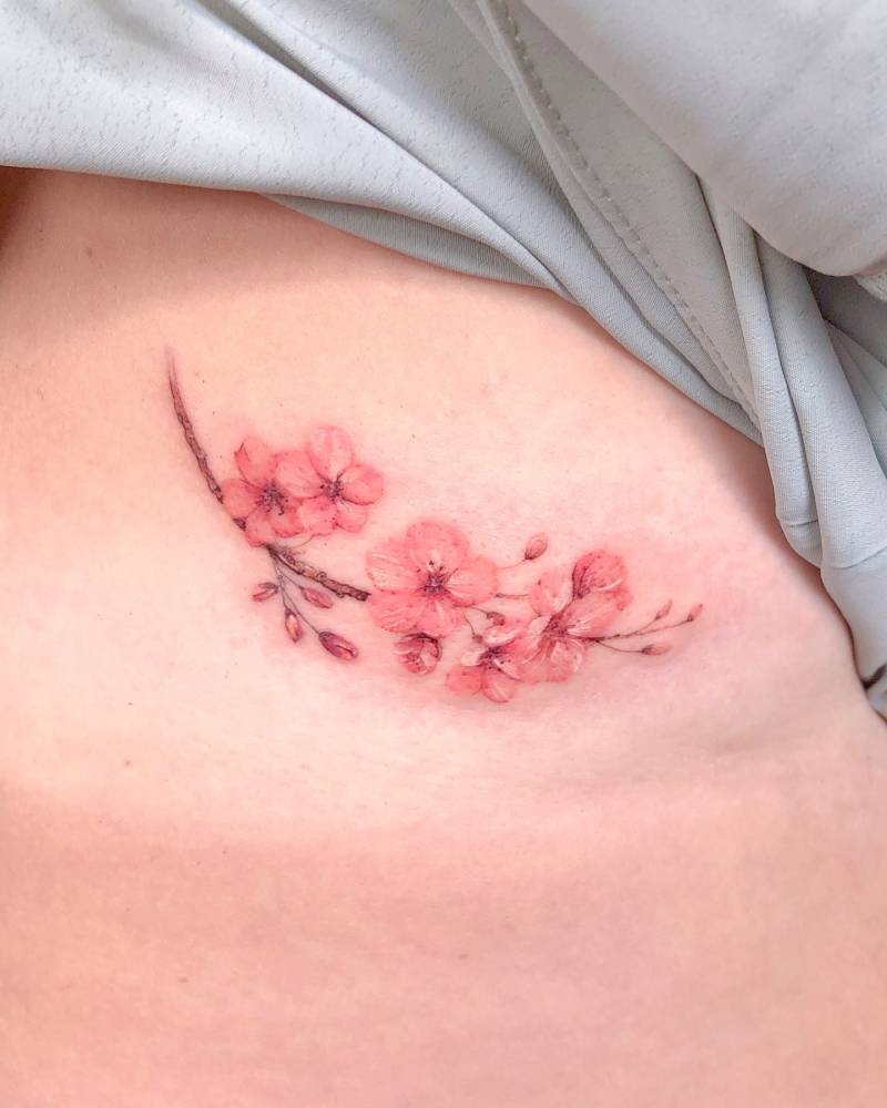 Watercolor style cherry blossom tattoo located on the rib.