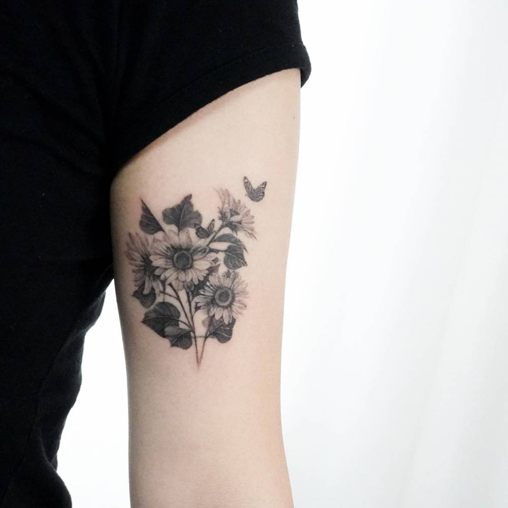 Sunflower tattoo located on the tricep, micro-realistic style.