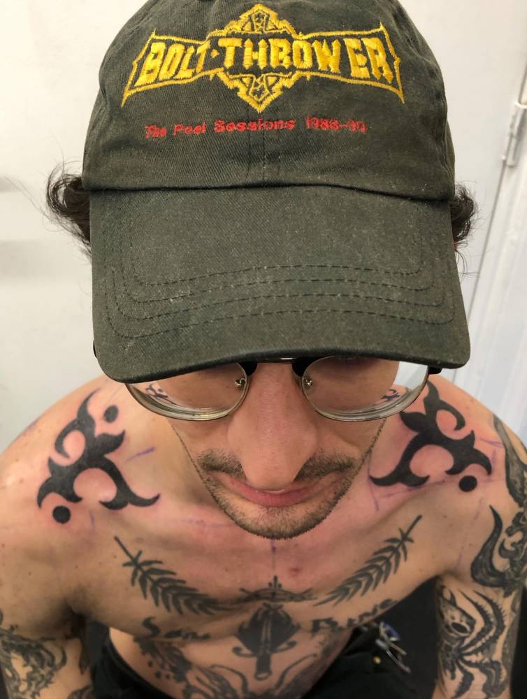 Individual matching ornamental design tattooed on the top of shoulders.