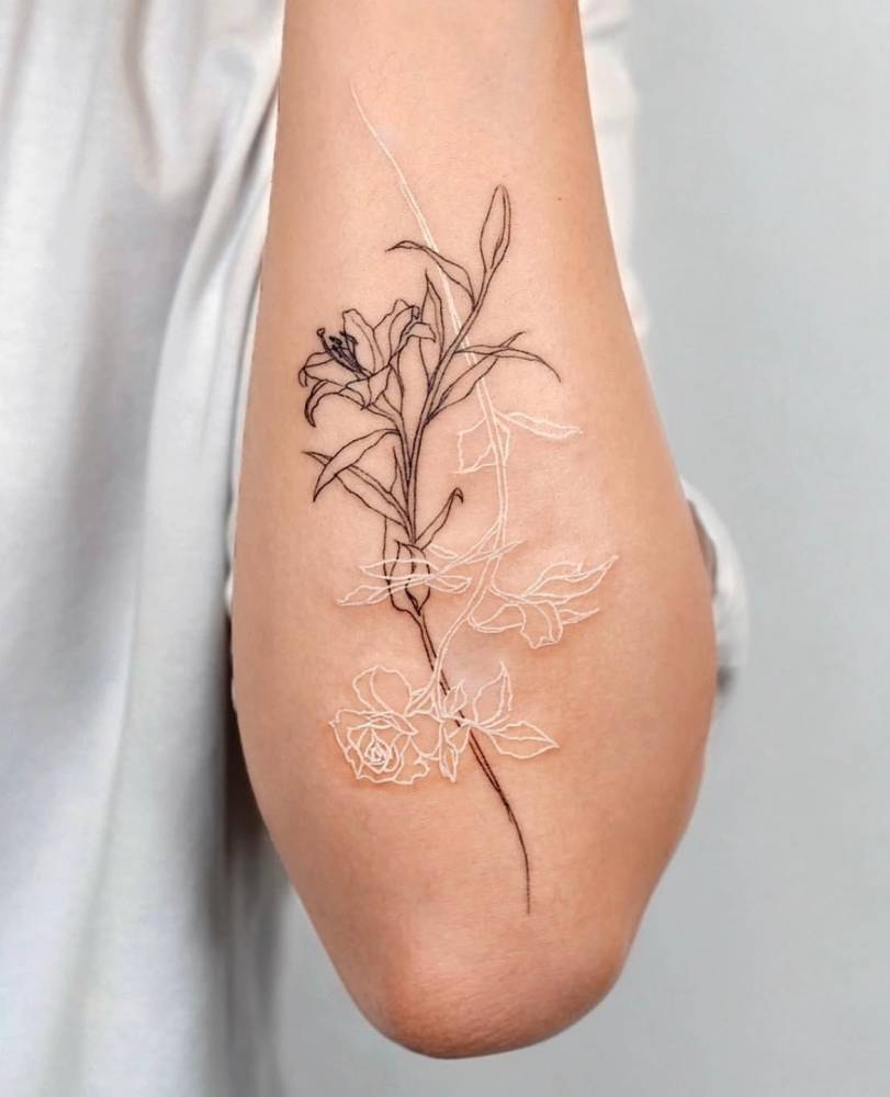Lily flower and white rose tattoo located on the forearm.