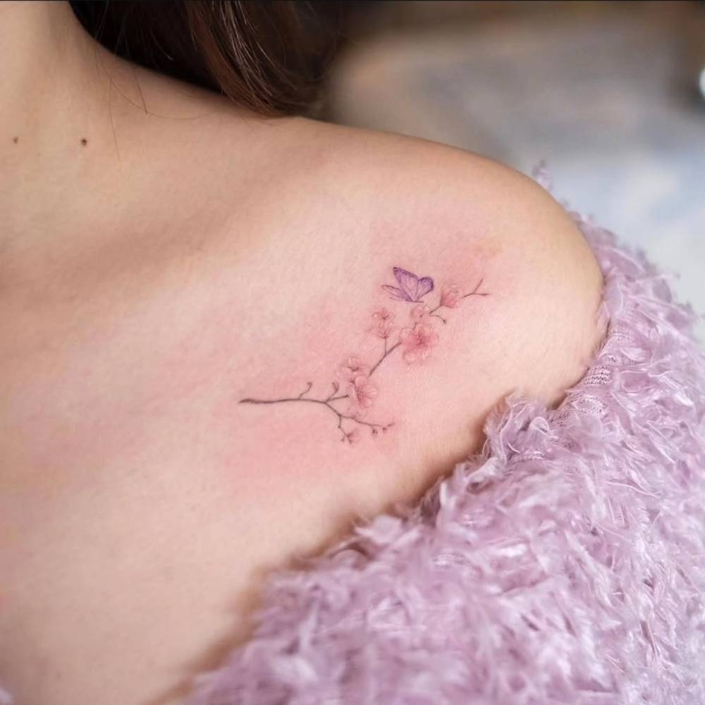 Watercolor style cherry blossom and purple butterfly tattoo located on the shoulder.
