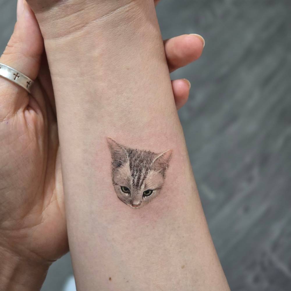Cat portrait tattoo located on the wrist, done in micro-realism.