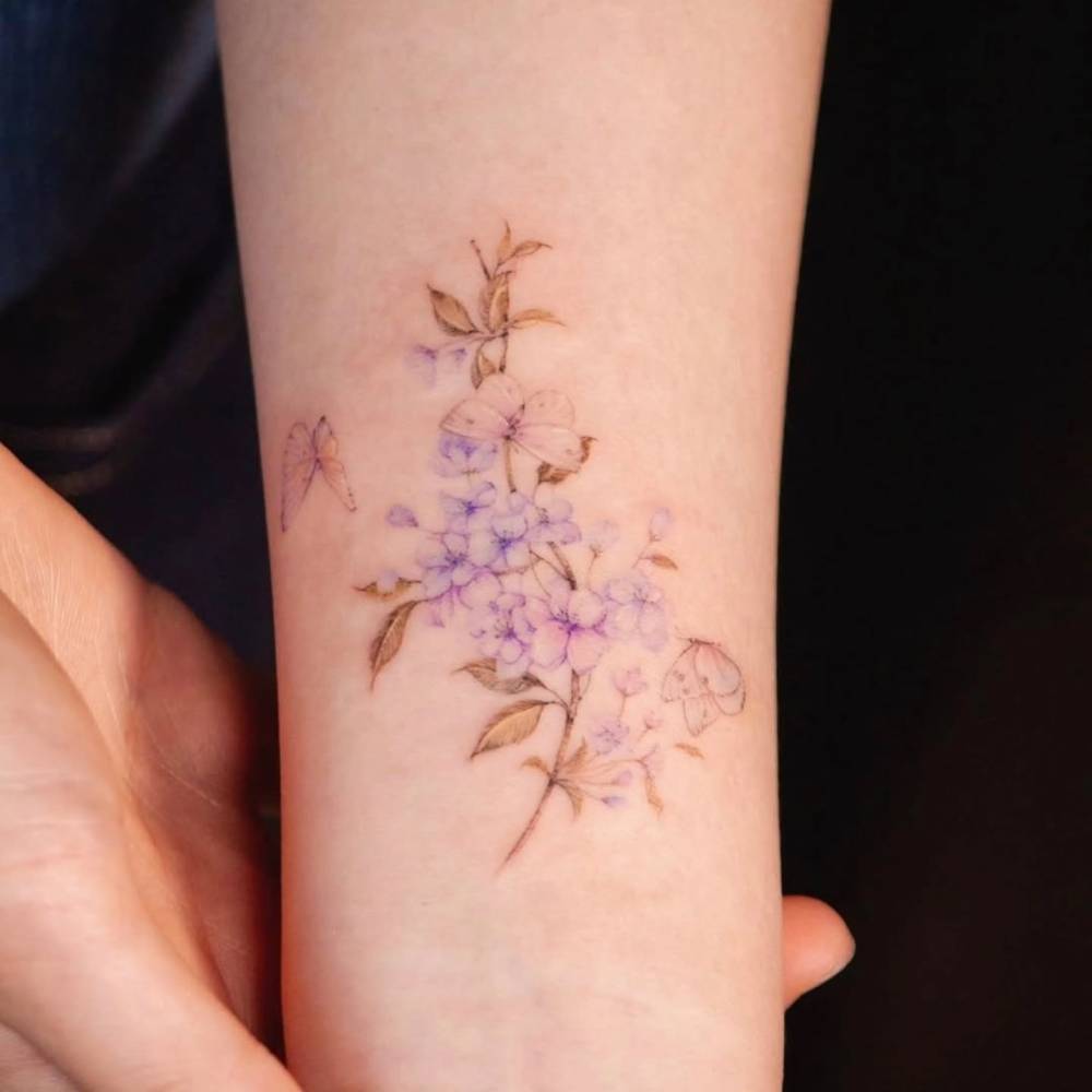 Watercolor style cherry blossom and butterflies tattoo located on the wrist.