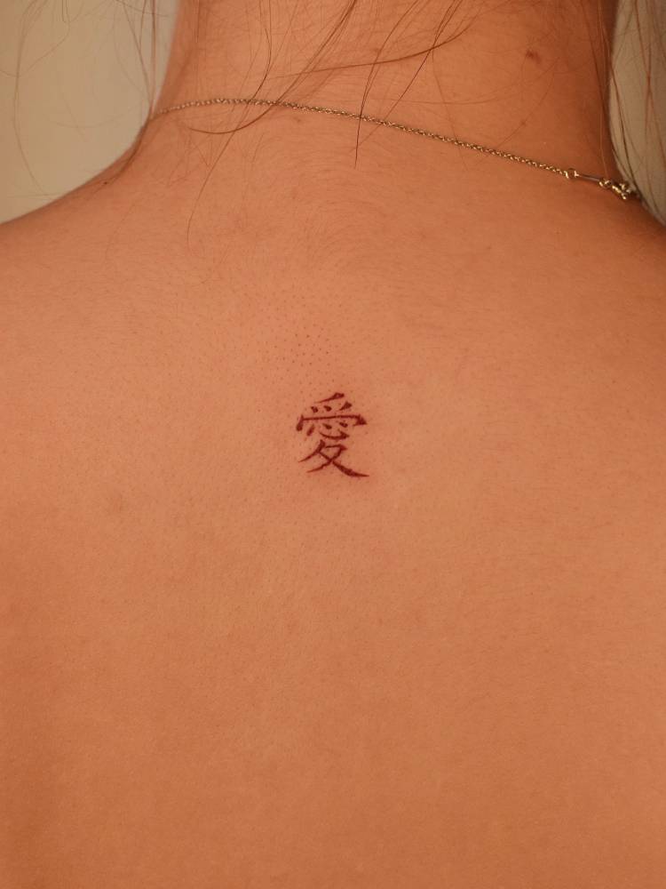 Chinese character tattoo located on the upper back.