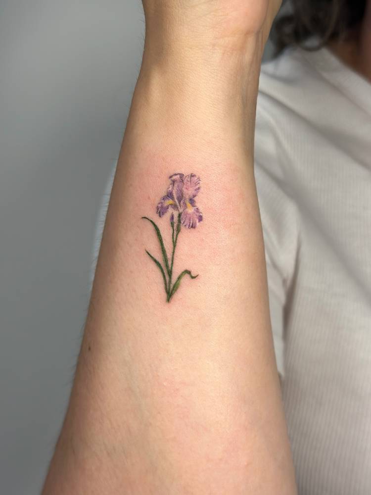 Watercolor style iris flower tattoo done on the wrist.