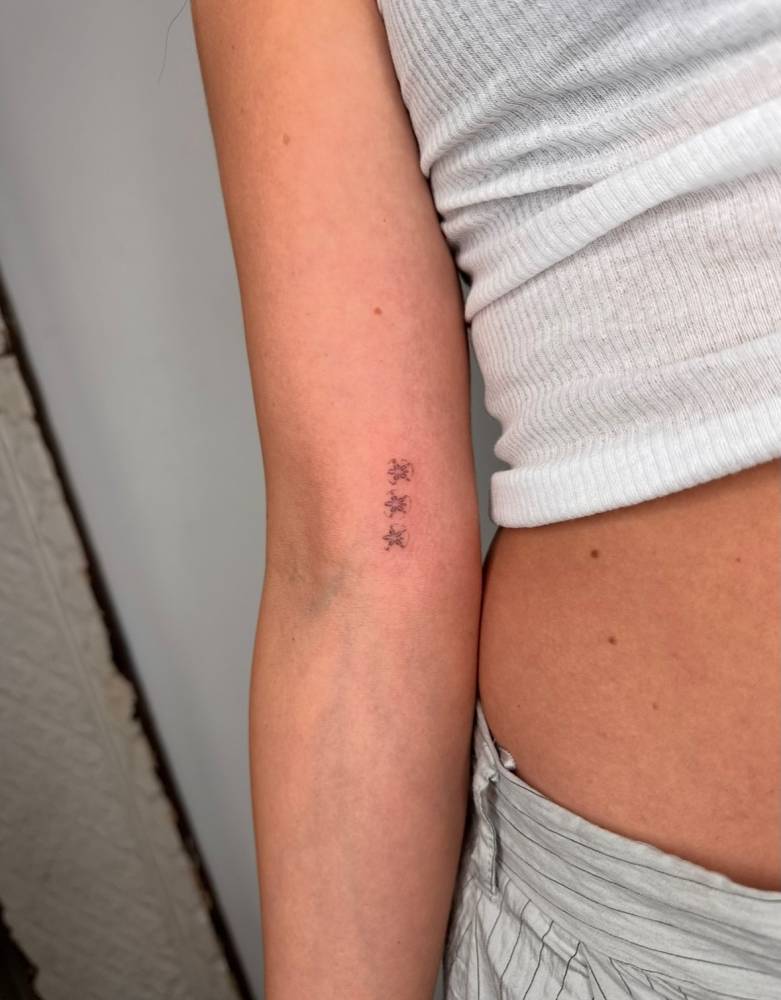 Ornamental little stars tattooed on the inner arm.