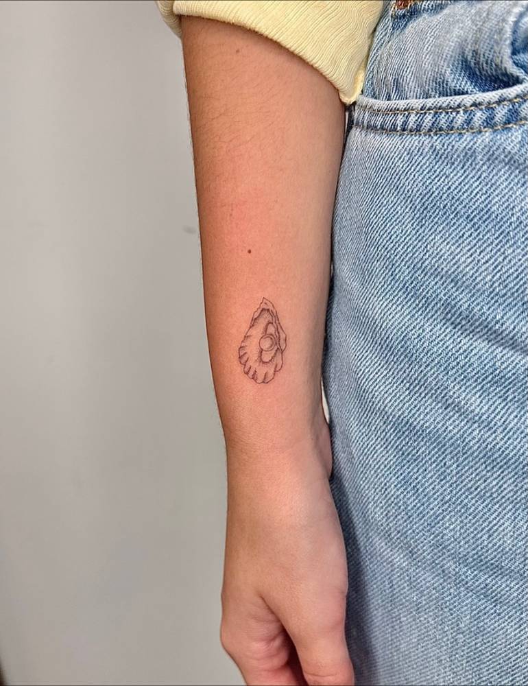 Scallop tattoo located on the wrist, illustrative style.