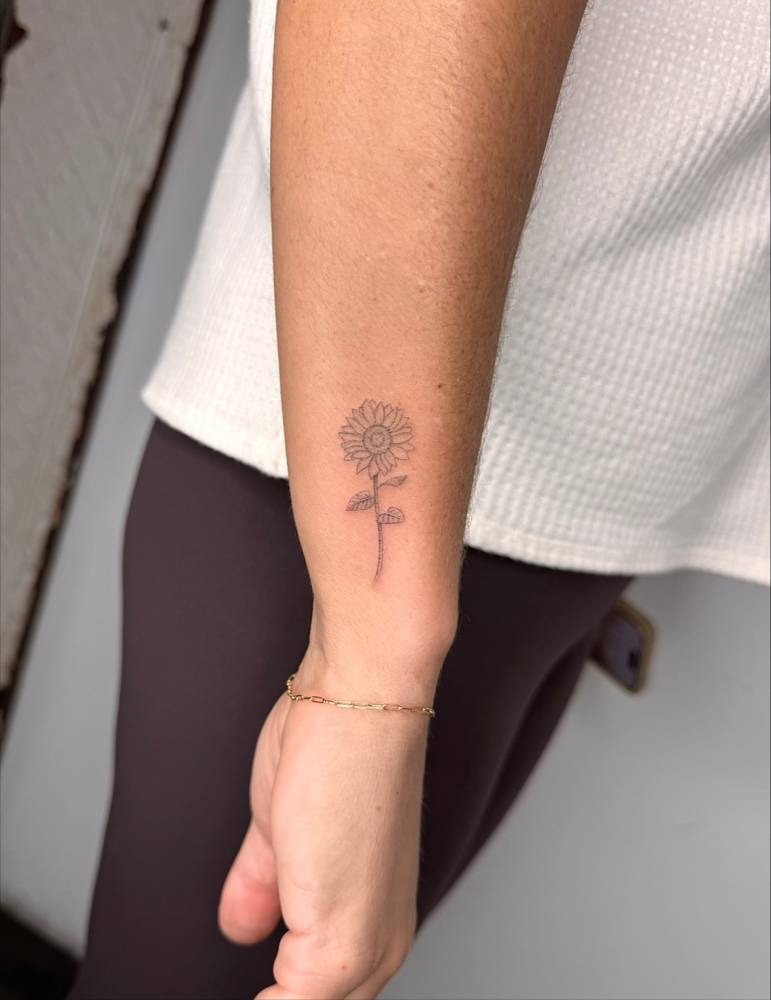 Healed sunflower tattoo located on the wrist, fine line style.