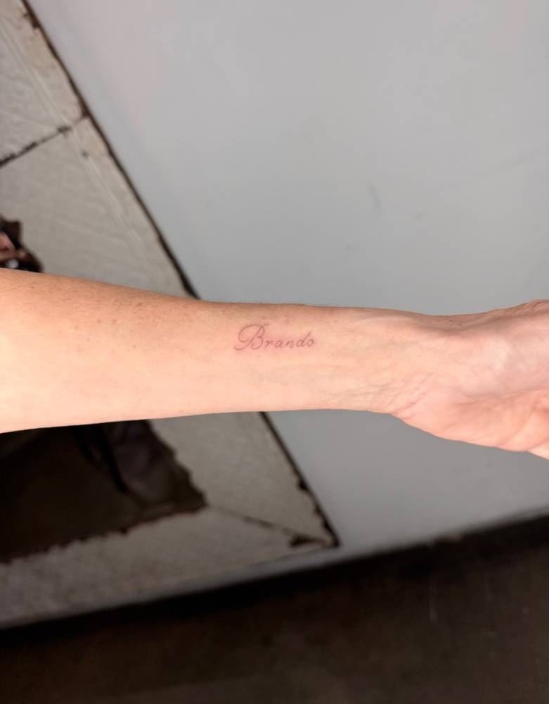 Lettering tattoo of the name "Brando" located on the wrist.