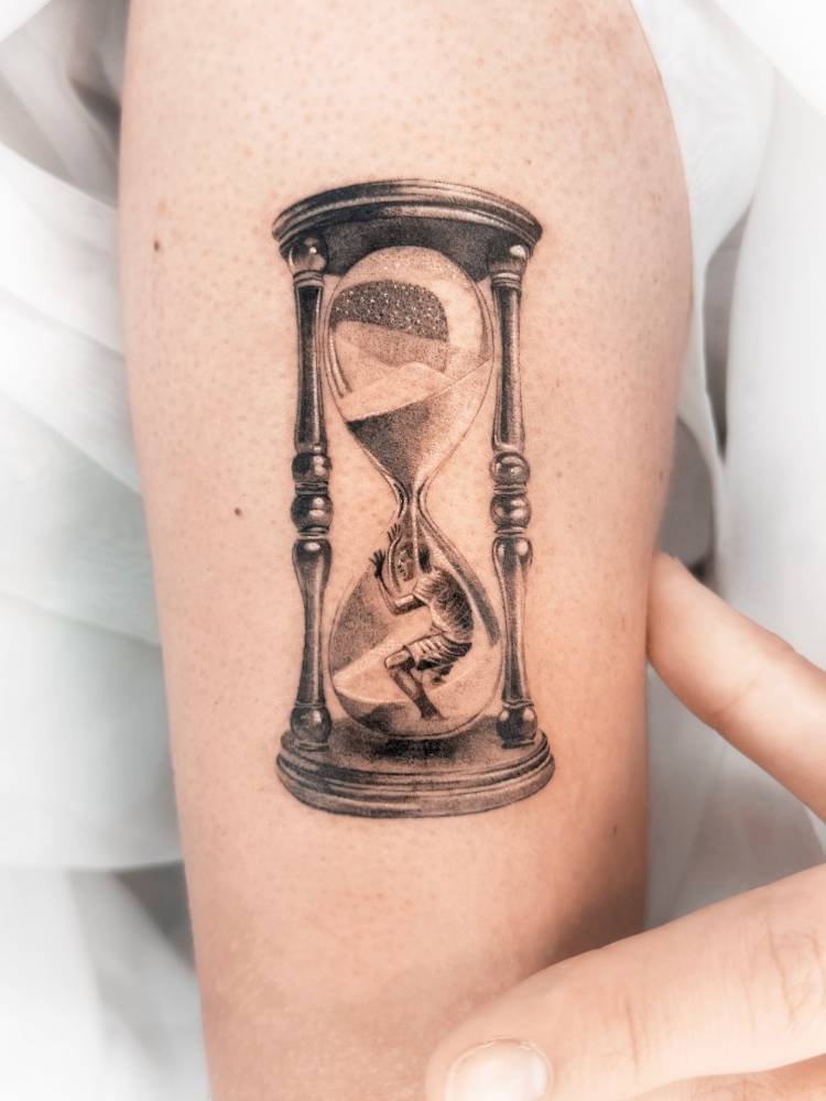 Hourglass tattoo located on the upper arm, done in micro-realistic style.