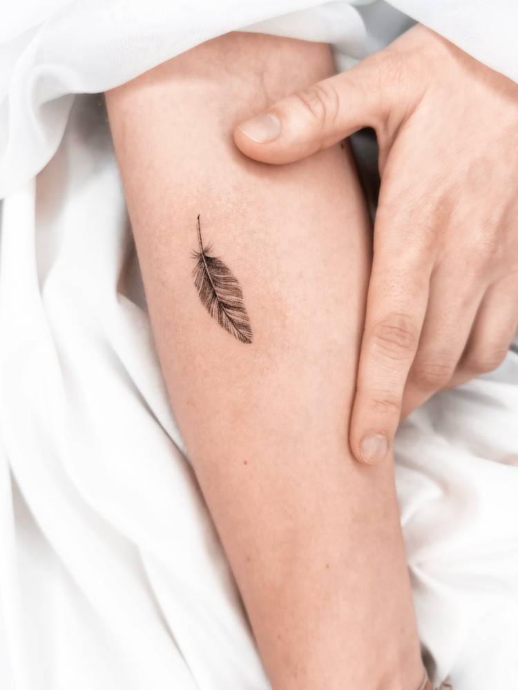 Micro-realistic style feather tattoo located on the inner forearm.
