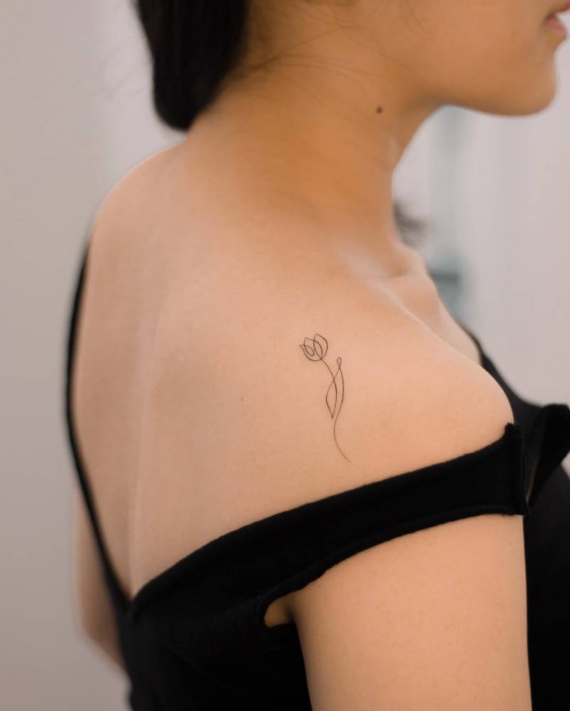 One line tulip tattoo located on the shoulder.