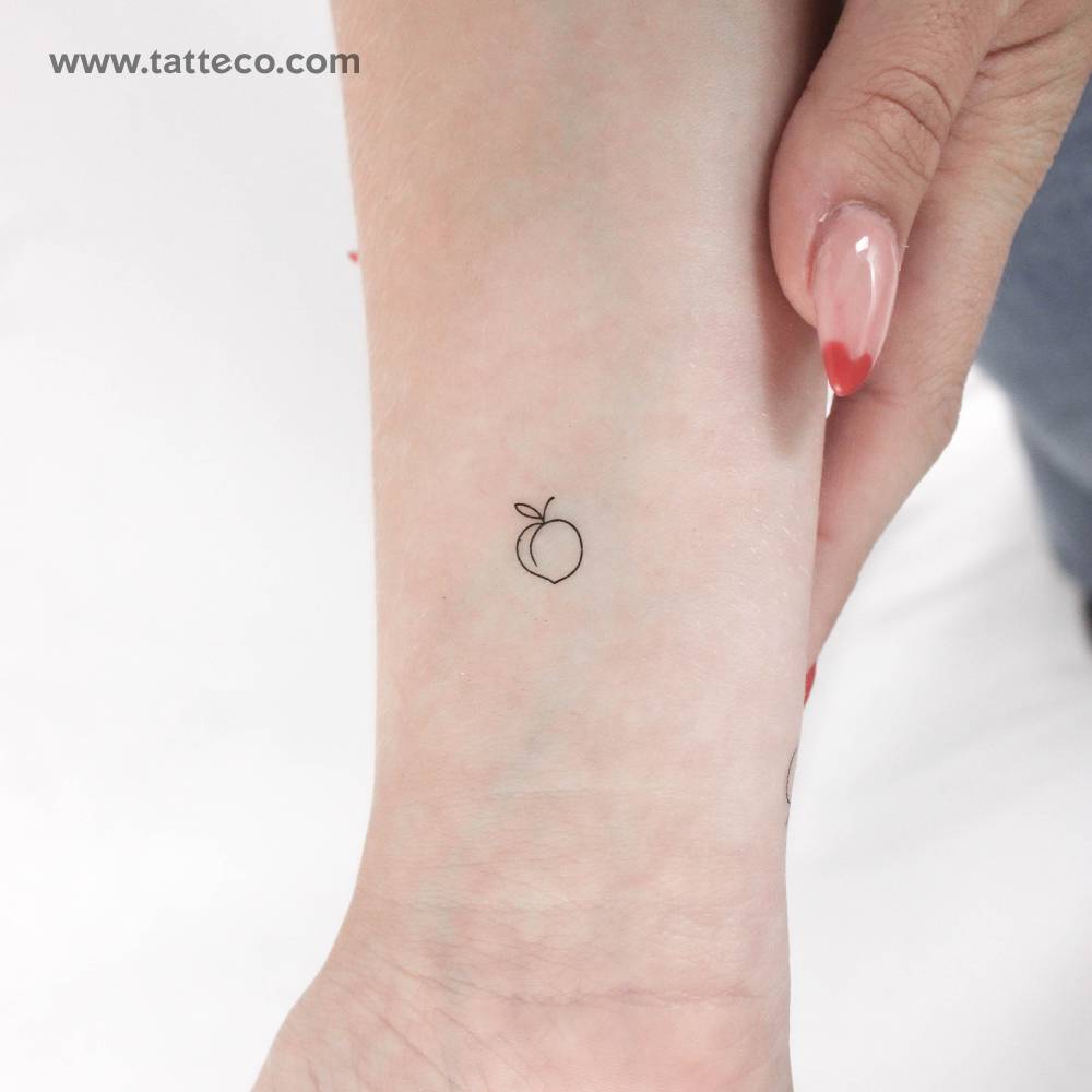 Tiny minimalistic peach temporary tattoo located on the wrist.
