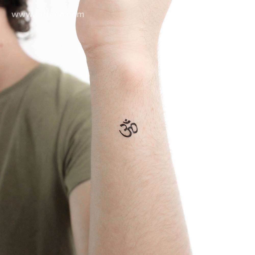Tiny minimalistic Om temporary tattoo placed on the wrist.