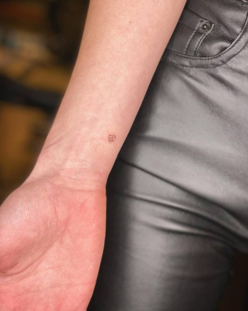 Tiny minimalistic Om tattoo located on the wrist.