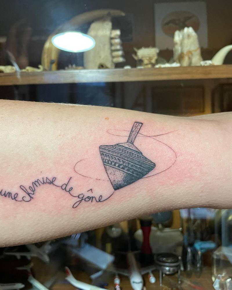 Spinning top tattoo in engraving style placed on the inner arm.