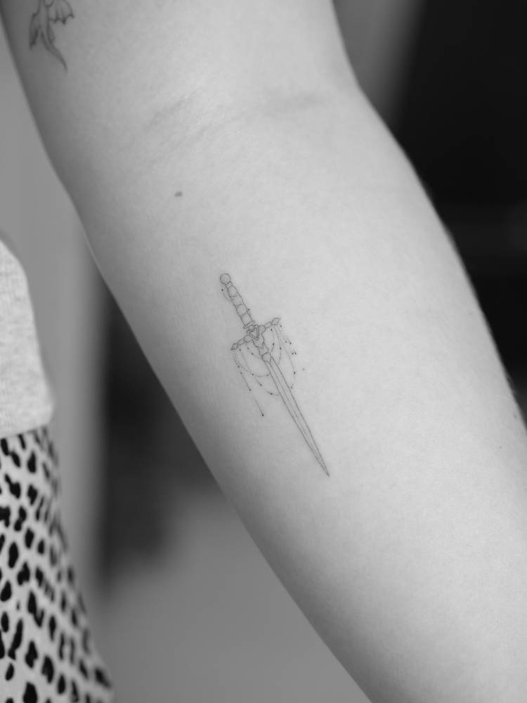 Fine line style sword tattoo located on the inner forearm.