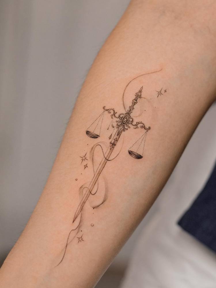 Sword and scale tattoo located on the inner forearm.
