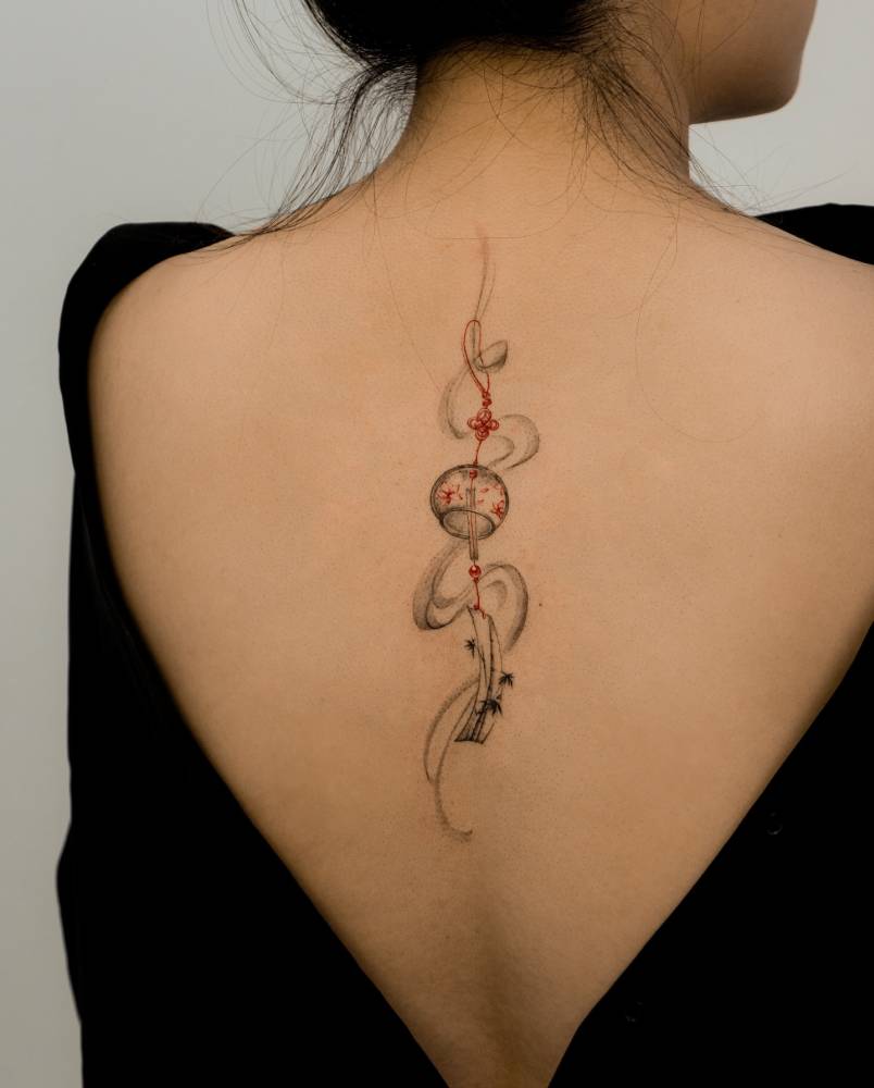 Norigae tattoo in illustrative style done on the upper back.