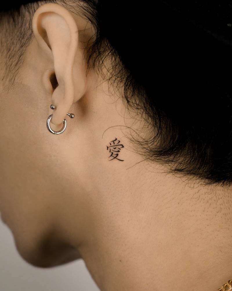 Little Chinese character tattoo placed behind the ear.