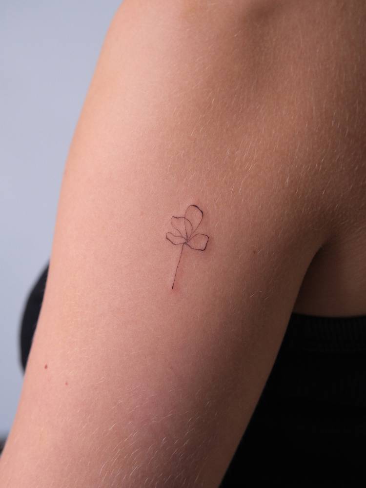 Fine line style flower tattoo located on the upper arm.