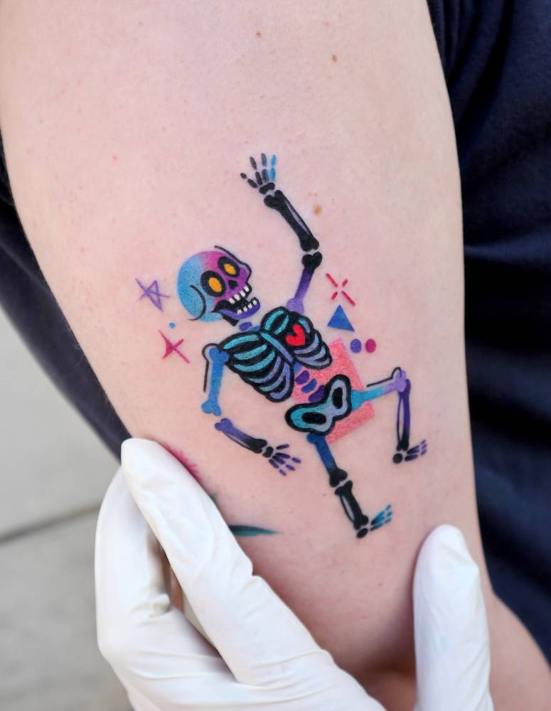Skeleton tattoo in pop art style done on the upper arm.