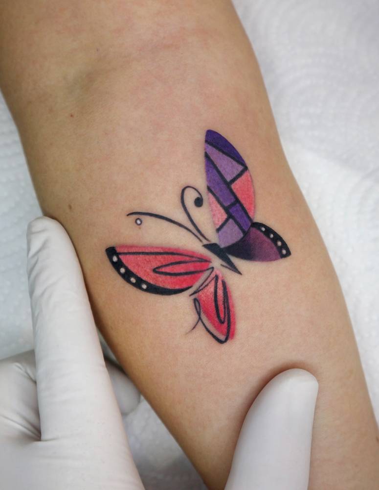 Butterfly tattoo in pop art style located on the inner forearm.