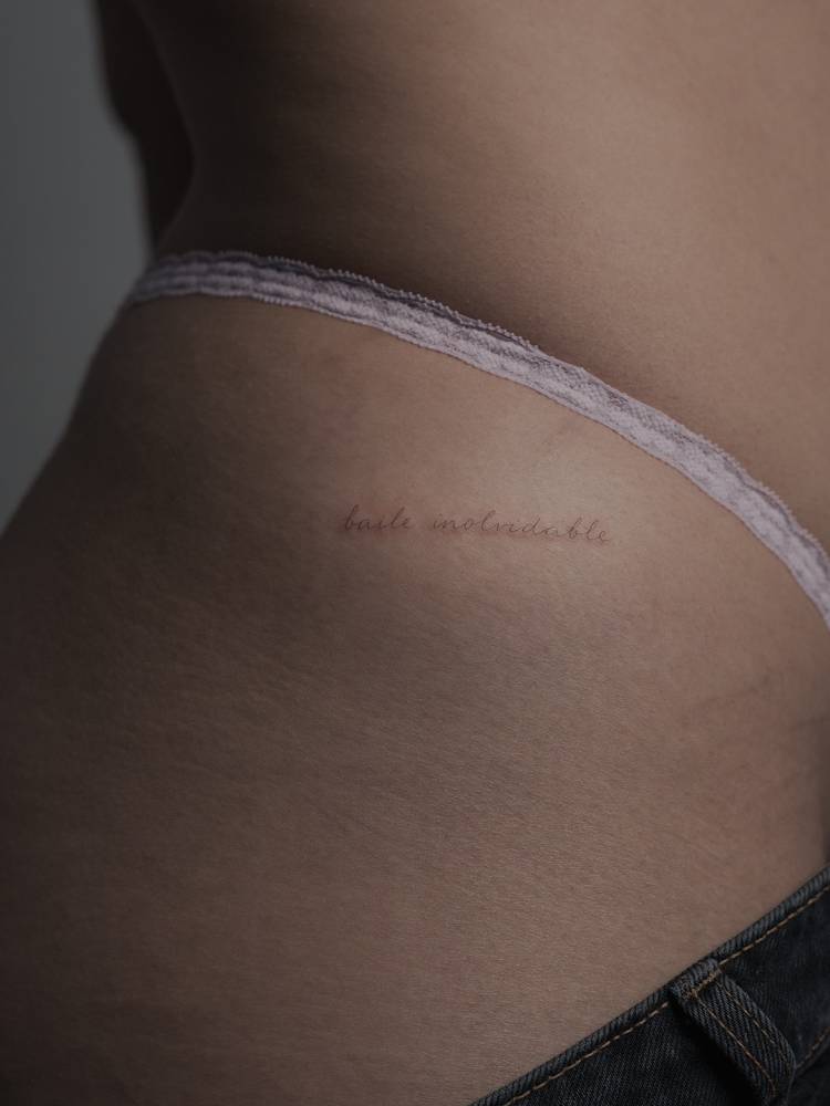 "Baile inolvidable" lettering tattoo handwritten on the hip.