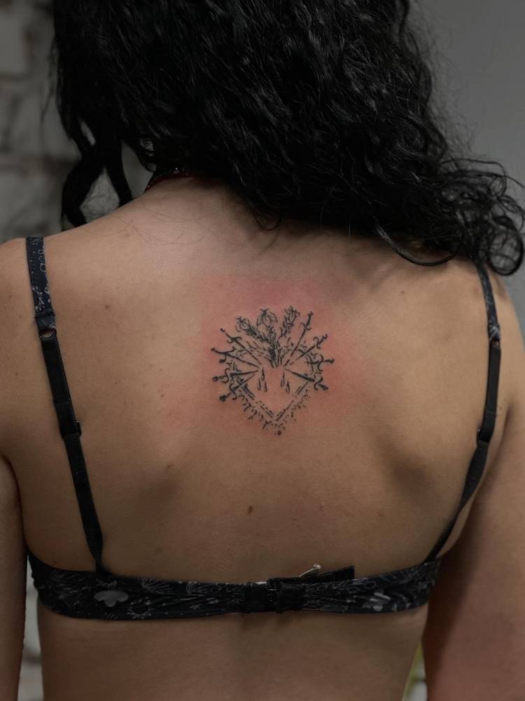 Sacred heart tattoo located on the upper back.