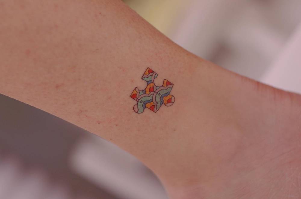 Puzzle piece tattoo located on the ankle, done in illustrative style.