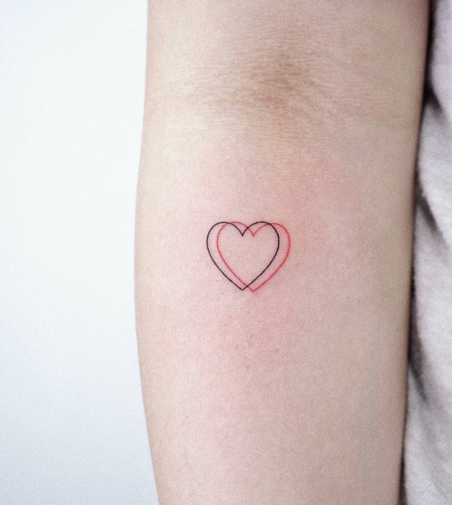 Fine line hearts tattooed on the inner forearm, minimalistic style.