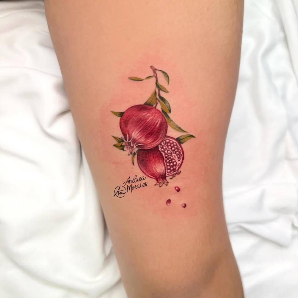 Pomegranate tattoo located on the thigh, micro-realistic style.