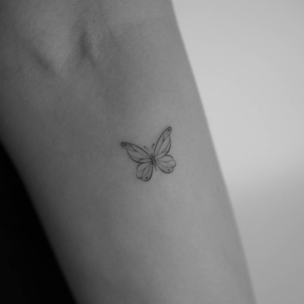 Little butterfly tattoo in fine line style done on the inner forearm.