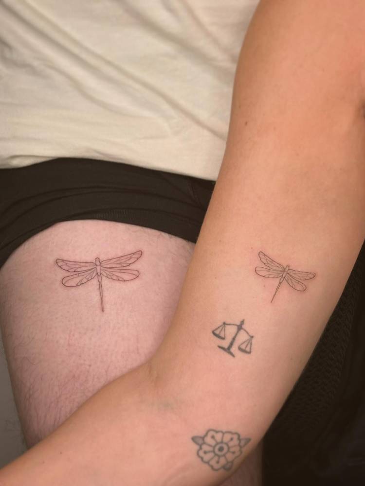 Matching fine line style dragonfly tattoo for couple.