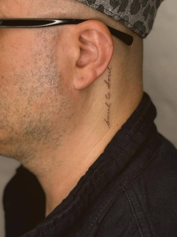"Soul to soul" lettering tattoo located behind the ear.